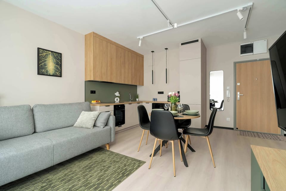 A dining space with a round table, black chairs, and a well-lit interior, seamlessly connected to the kitchen and living room.