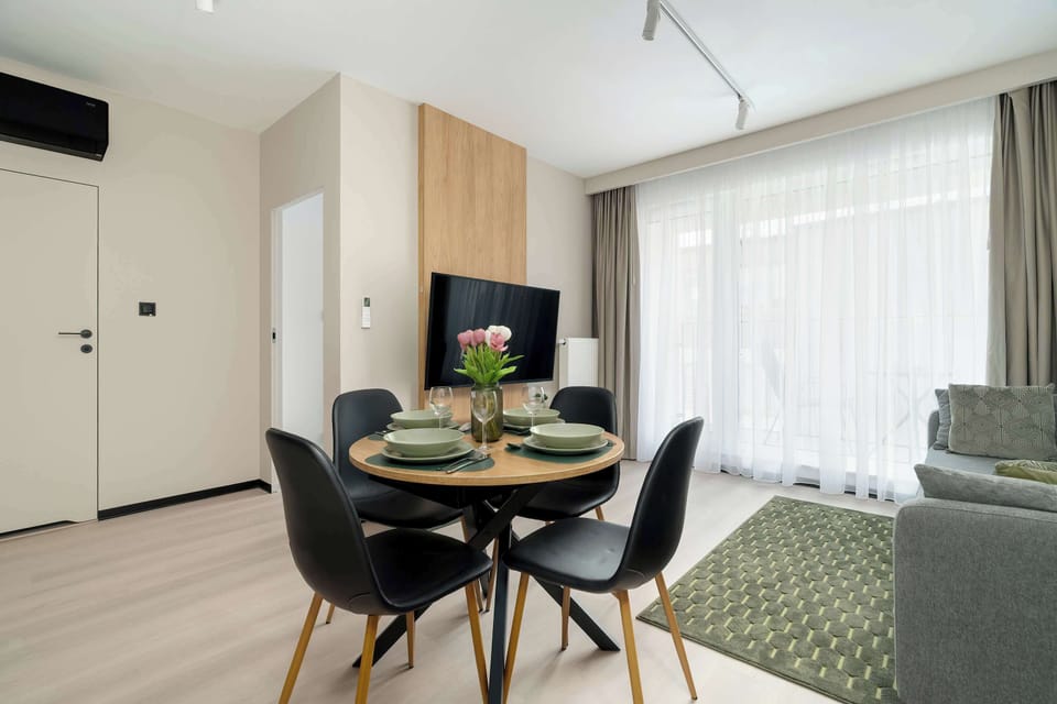 Another angle of the open-concept living space, featuring a dining table, sofa, and kitchen area.