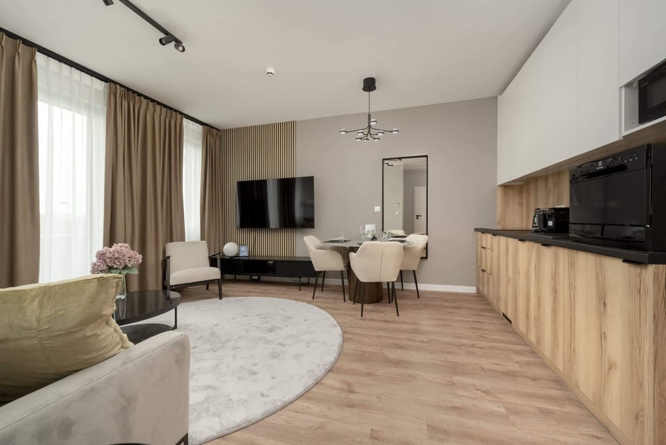 A cozy living room with a sectional sofa, round rug, and modern kitchen in the background.