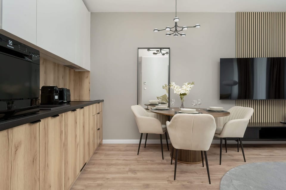 A galley kitchen with glossy black lower cabinets, wooden upper cabinets, and stainless steel appliances.