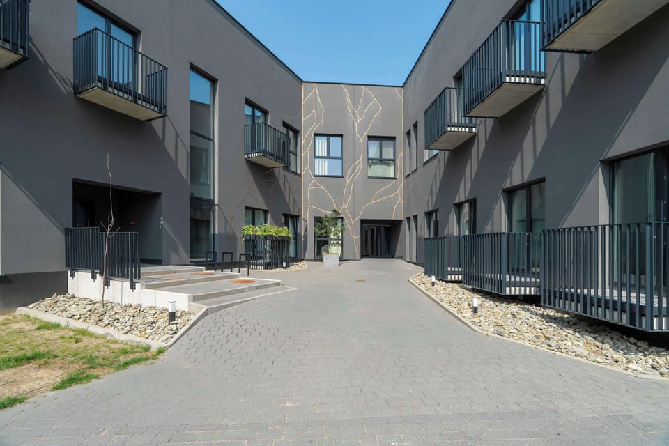 An exterior view of a modern residential building surrounded by greenery, with easy access to urban infrastructure.