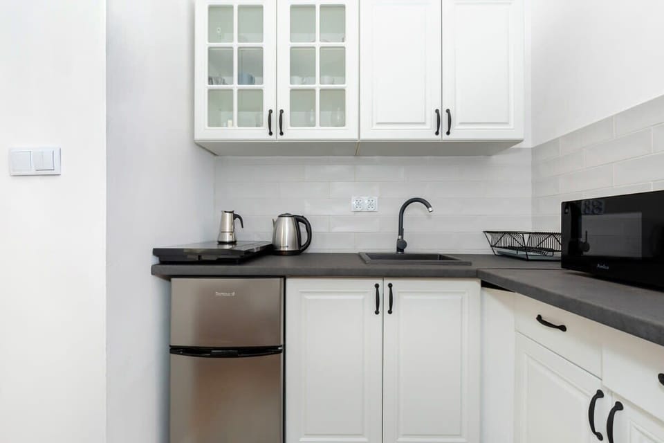 Functionally equipped kitchen with fridge, dining area, freezer, stove, microwave, kettle, cupboards, and toaster.