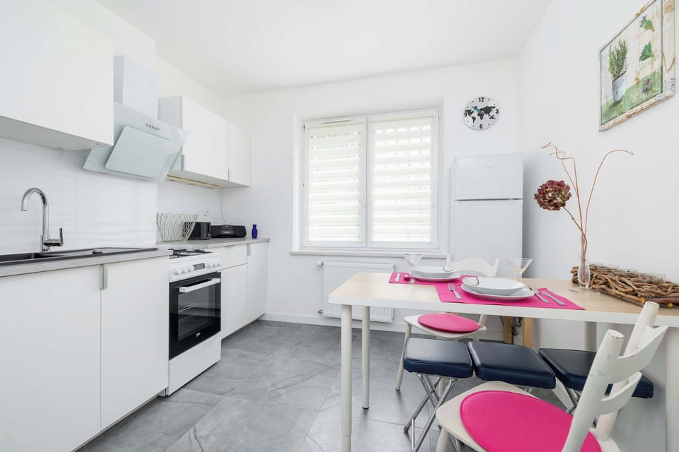 The kitchen area is equipped with modern appliances, including a washing machine, an oven, and a compact fridge. The white cabinetry maintains a sleek, organized look