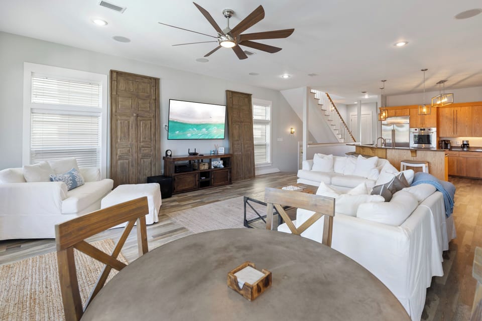Sink into plush white sofas in your open-concept living space, where coastal views on the flat-screen TV complement warm wood tones and soaring ceilings.