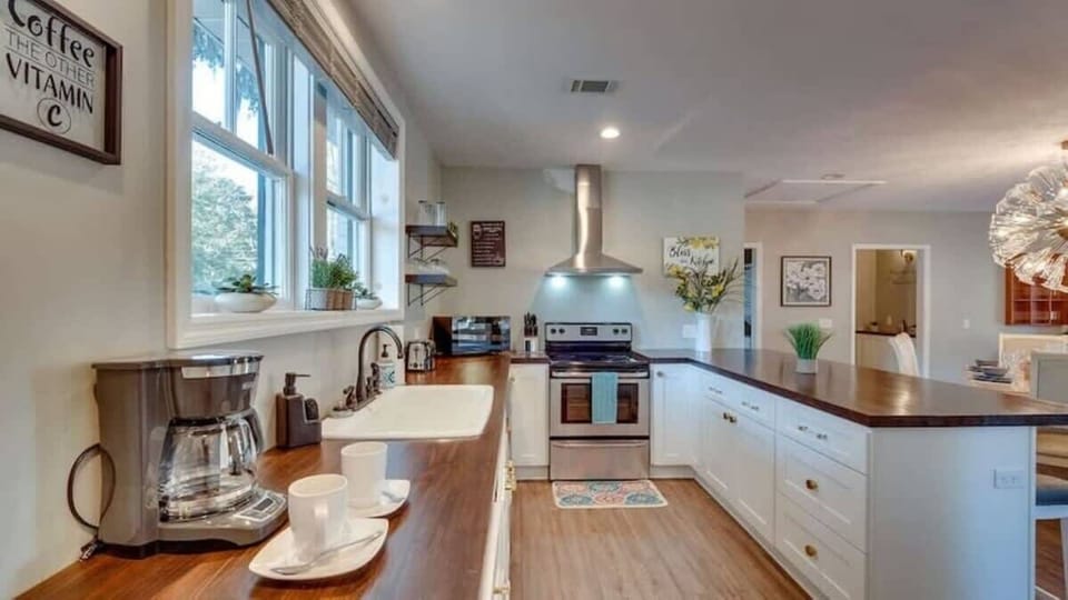 Clean, updated kitchen with white cabinets, wooden countertops, and stainless steel appliances.
