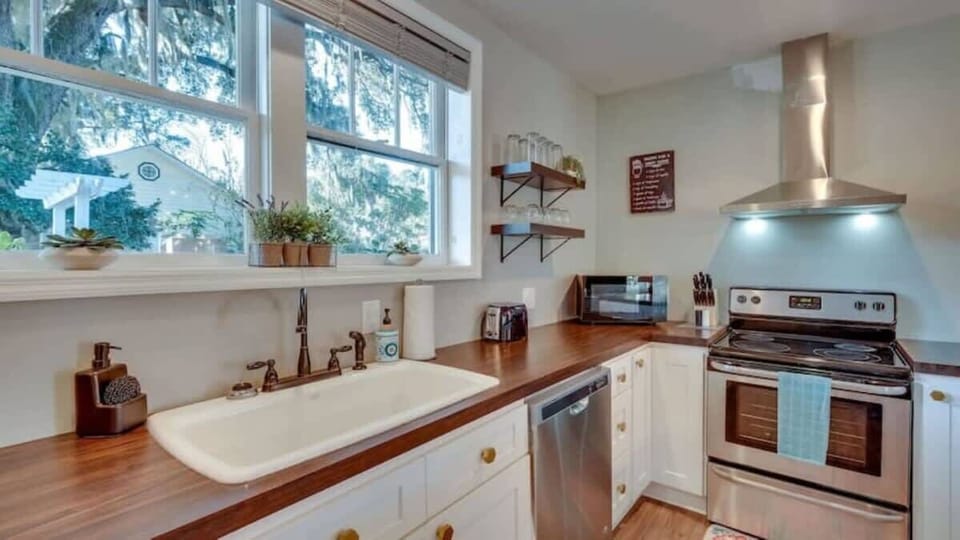 Clean, updated kitchen with white cabinets, wooden countertops, and stainless steel appliances.