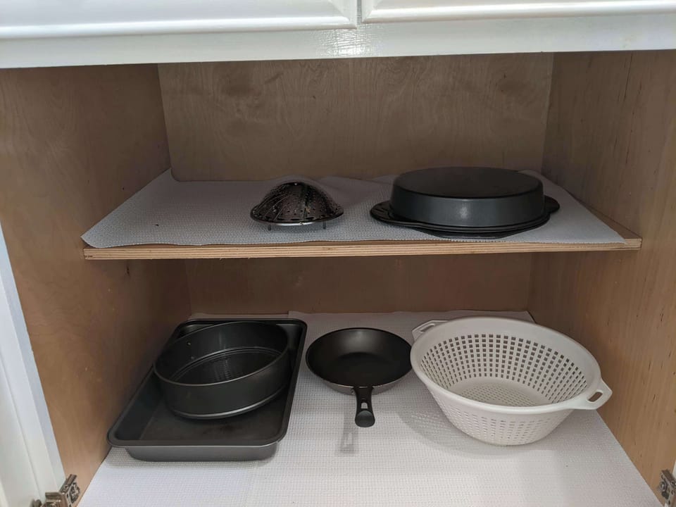Cookware storage showing skillets, baking pans, and other kitchen accessories.