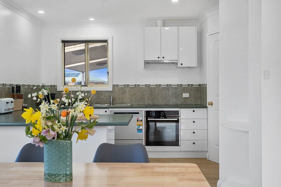 Cook up a storm in a bright kitchen with modern appliances, dining table & fresh flowers for that ho
