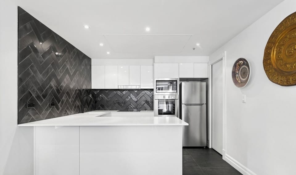 A clean, minimalist kitchen area with a central white island.