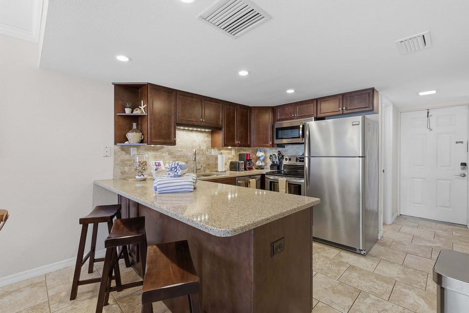 Cook and gather in this updated coastal kitchen featuring granite countertops, stainless steel appliances, and a convenient breakfast bar. A stylish beach stay designed for comfort and easy vacation living.