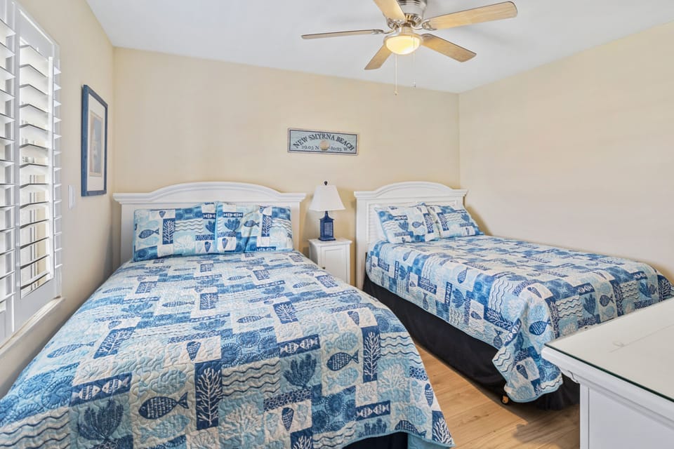 Relax in this airy guest room featuring two comfy beds with ocean-inspired bedding, perfect for unwinding after a fun-filled day of sun, sand, and surf at your beach vacation retreat.