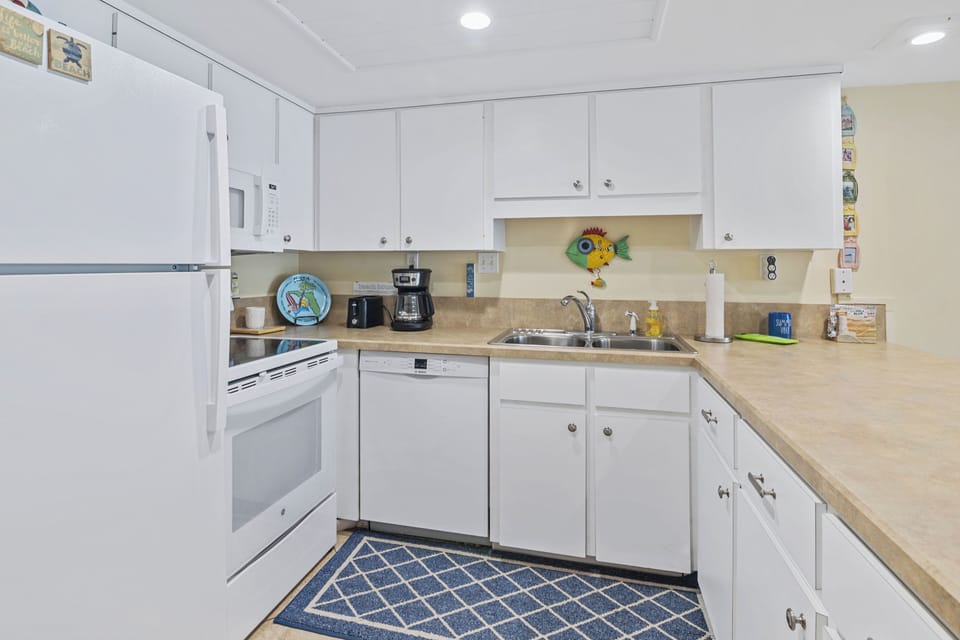 Cook with ease in this cheerful beach-themed kitchen featuring modern appliances, spacious counters, and all the essentials for preparing delicious meals during your coastal getaway.