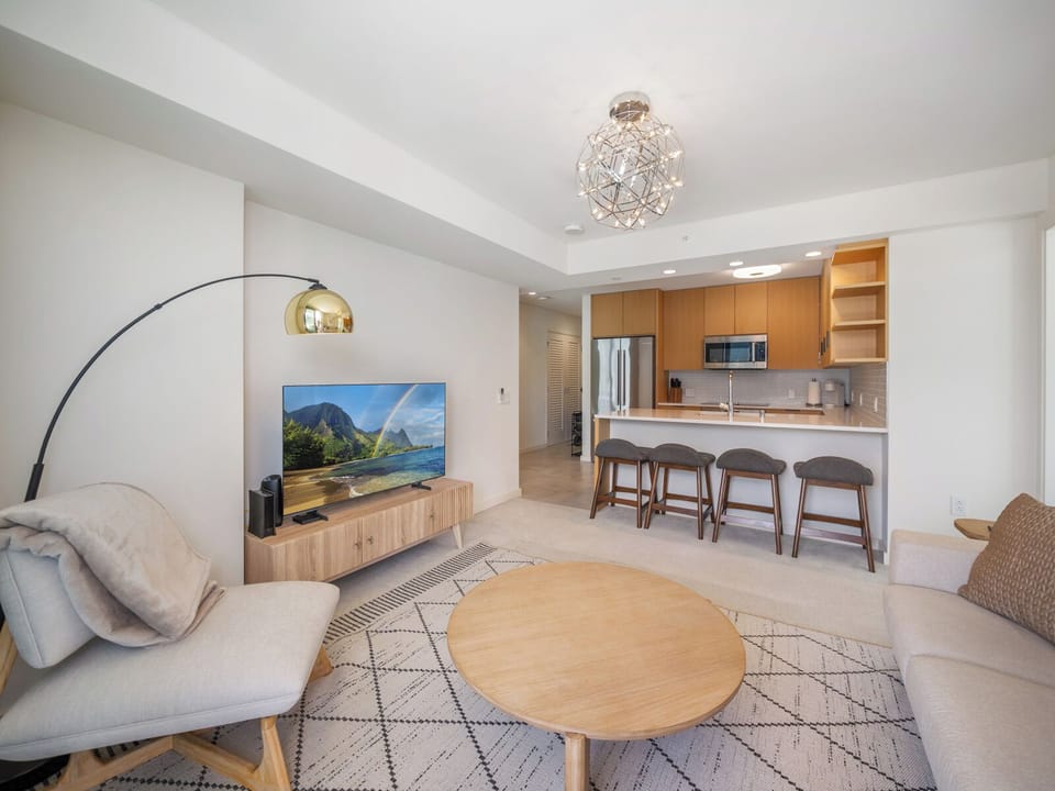 Living Room - Share meals in a dining space that celebrates its modern decor. Where a breakfast bar meets a cozy living room lounge with a sofa and smart TV. A welcoming space to share meals, relax, and enjoy time together near Ala Moana and Waikiki.