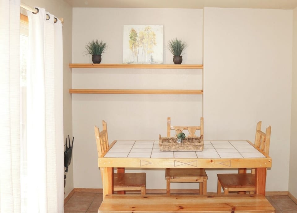 Gather around your rustic tile-top table, where warm wood tones and natural light create the perfect spot for morning coffee or evening meals together.