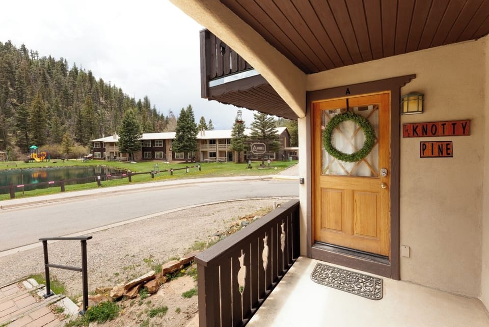 The property entrance welcomes you with a charming green wreath and mountain views, framed by forested hillsides and the peaceful community beyond.