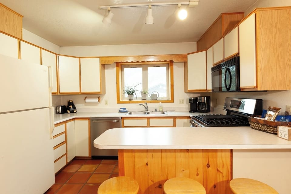Prepare meals in your fully equipped kitchen, featuring warm wood cabinetry, modern appliances, and ample counter space for all your culinary needs.