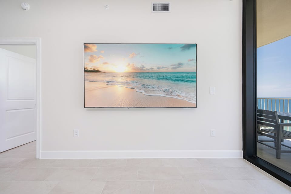 Unwind in the inviting living area, featuring a large TV and a view of the balcony, perfect for relaxation