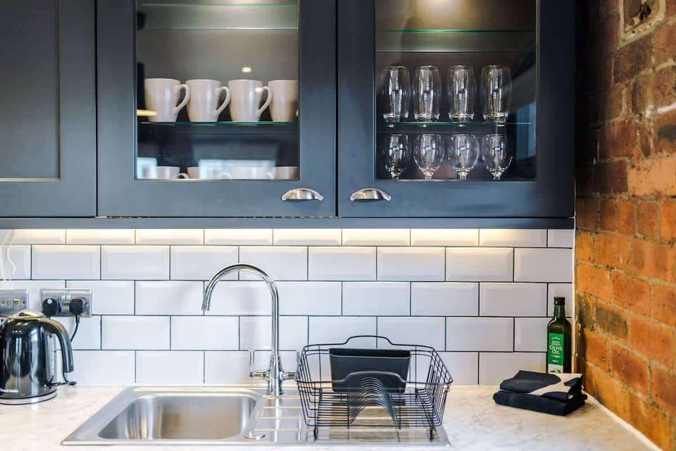 Contemporary kitchen with dark units, built-in appliances, under-cabinet lighting, and a chic dining setup.