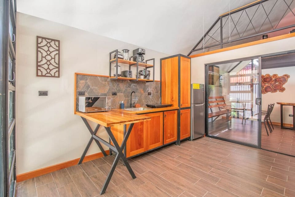 Modern kitchen with wooden finishes, open shelving, and dining area access, Aloki Kiré 2, Playa Chiquita, Costa Rica.