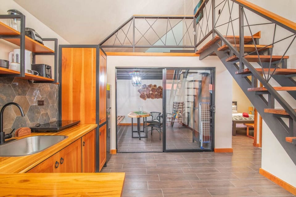 Open-concept kitchen with wooden finishes, mezzanine stairs, and sliding glass doors leading to the terrace, Aloki Kalok 3 in Playa Chiquita