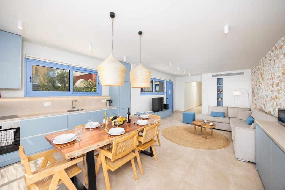 Open-plan living room with sofa, dining area, kitchen, A/C, WiFi internet, and satellite TV