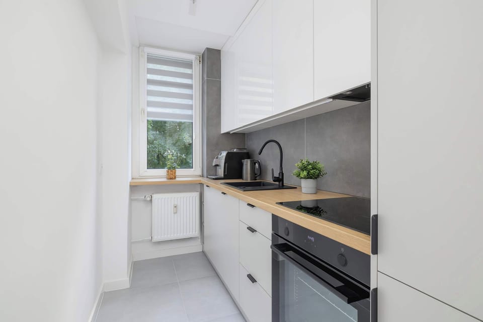 A clean angle of the kitchen featuring white cabinetry, wood counters, and a black sink.