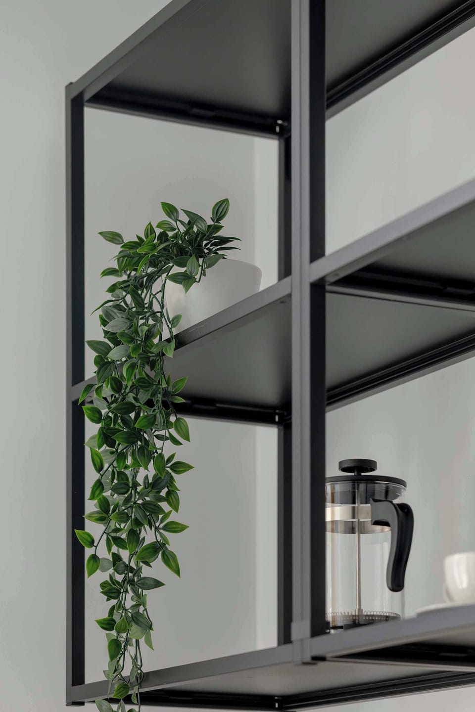 A modern shelf with decorative accents and a potted plant. Black metal and wood details add an industrial touch.