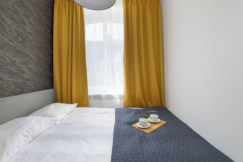 A bedroom with a double bed, crisp white walls, and yellow curtains. The neatly made bed invites relaxation and restful sleep.