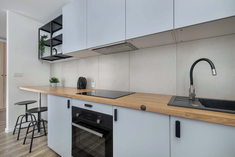 A compact and practical kitchenette with minimalist cabinets and a built-in stove. A single basin sink and sleek countertop complete the space.