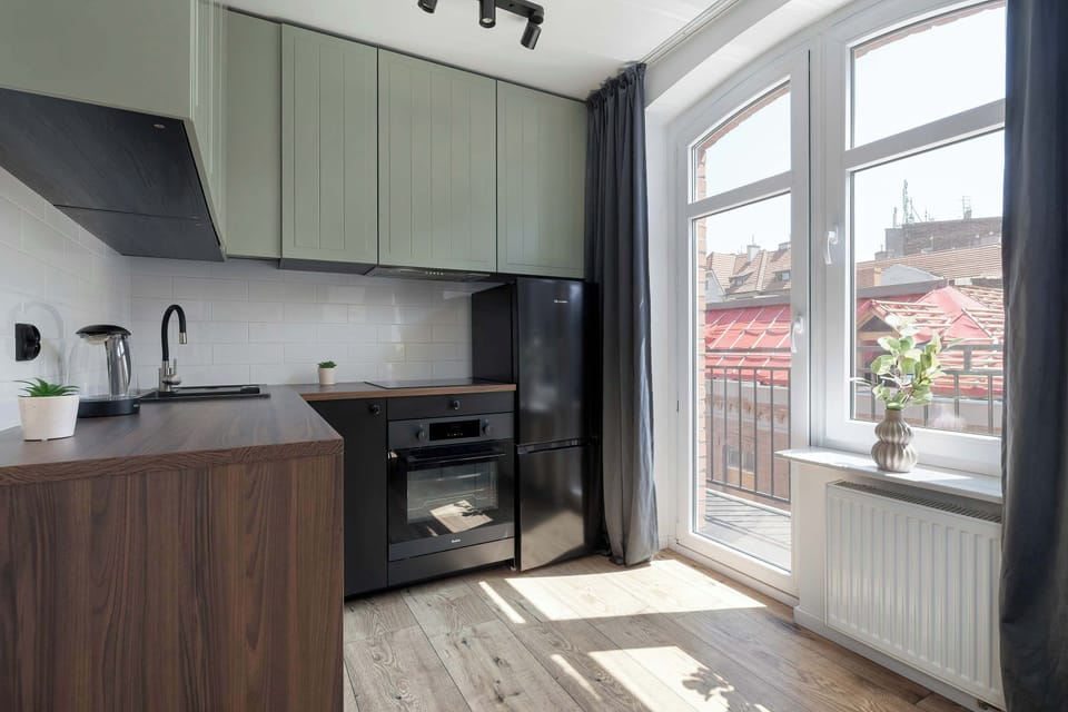 A modern kitchen with dark wood cabinets, a black oven, and a large window overlooking the city. Functional and stylish, ideal for everyday cooking.