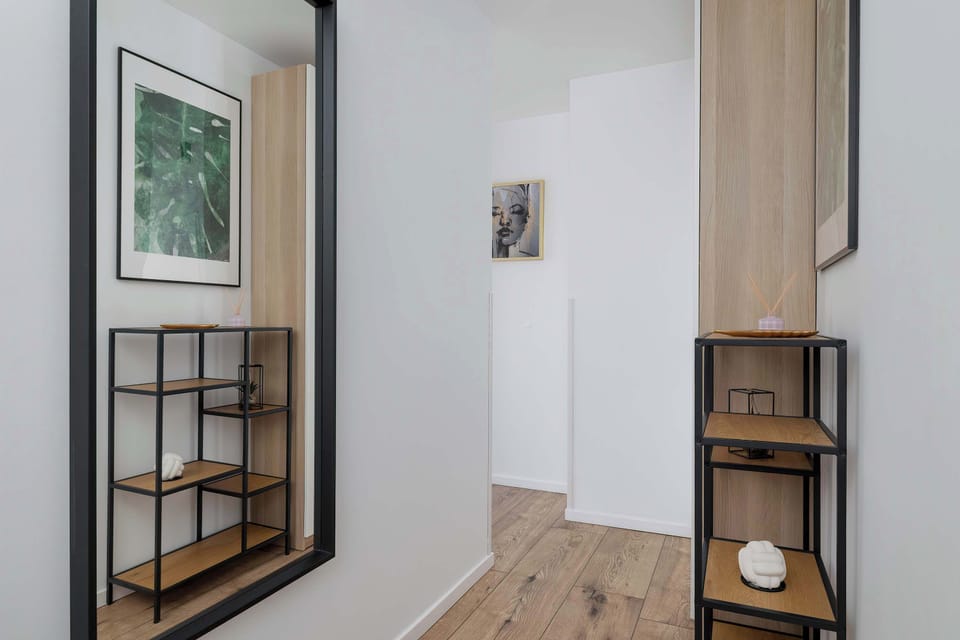  A stylish entrance area with a wall mirror, coat hooks, and a bench. Functional design meets aesthetic appeal.