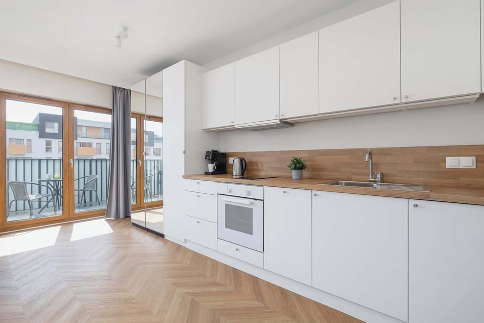 Clean kitchen design featuring white cabinetry and a wooden backsplash.