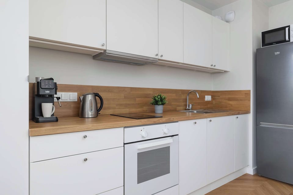Modern kitchenette with built-in appliances, kettle, and microwave, blending seamlessly into the living space.