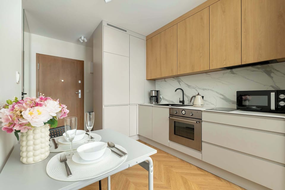 A fully equipped kitchenette featuring a sleek design, built-in appliances, and ample storage — ideal for preparing meals in a compact studio space.