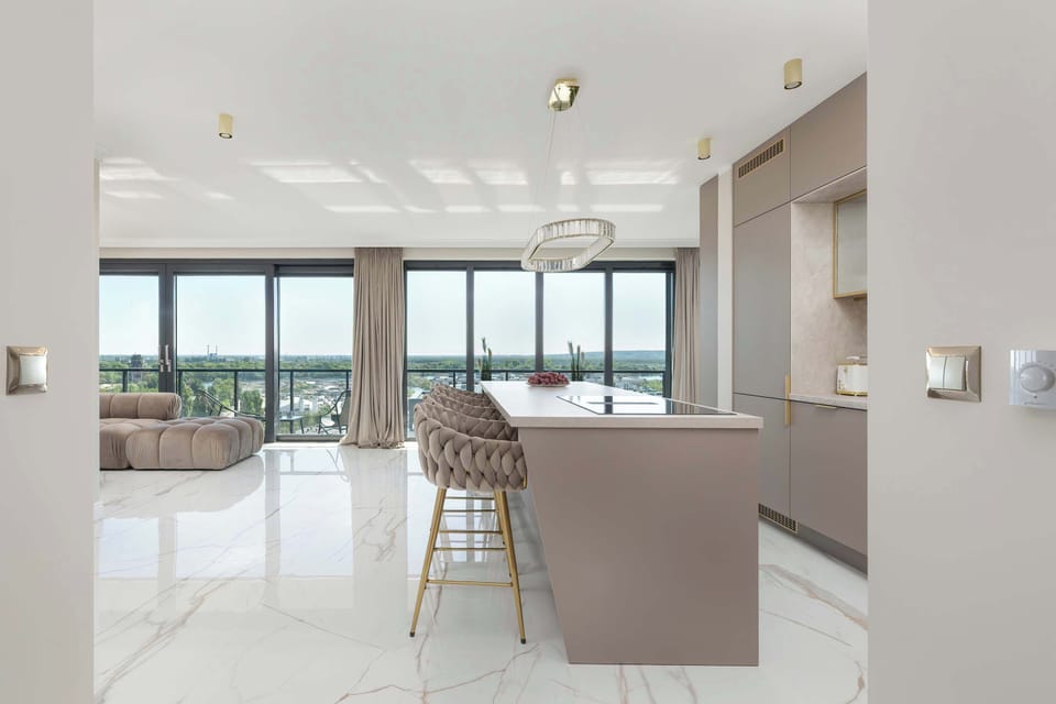 The stylish kitchenette connected to the dining room offers a modern kitchen island, high bar chairs and appliances such as an induction cooktop, oven and bean coffee maker.