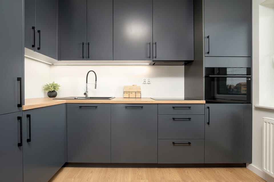 A sleek kitchen with dark cabinetry, under-cabinet lighting, and built-in appliances, creating a contemporary and functional cooking space.