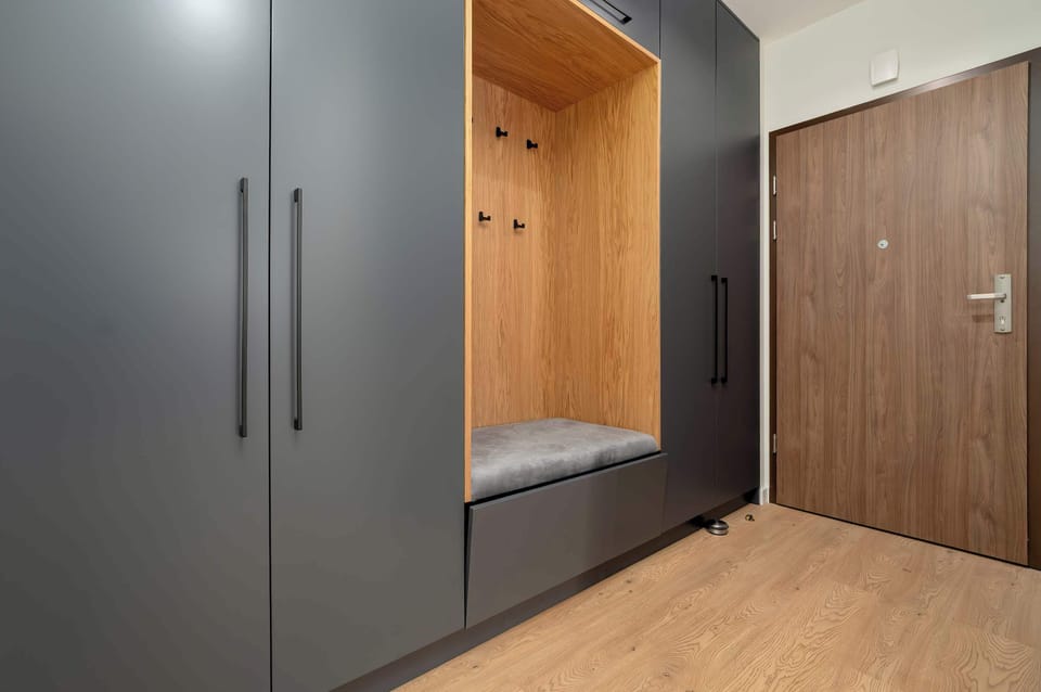 A hallway with soft lighting, a minimalist design, and wooden flooring leading to different rooms of the apartment.