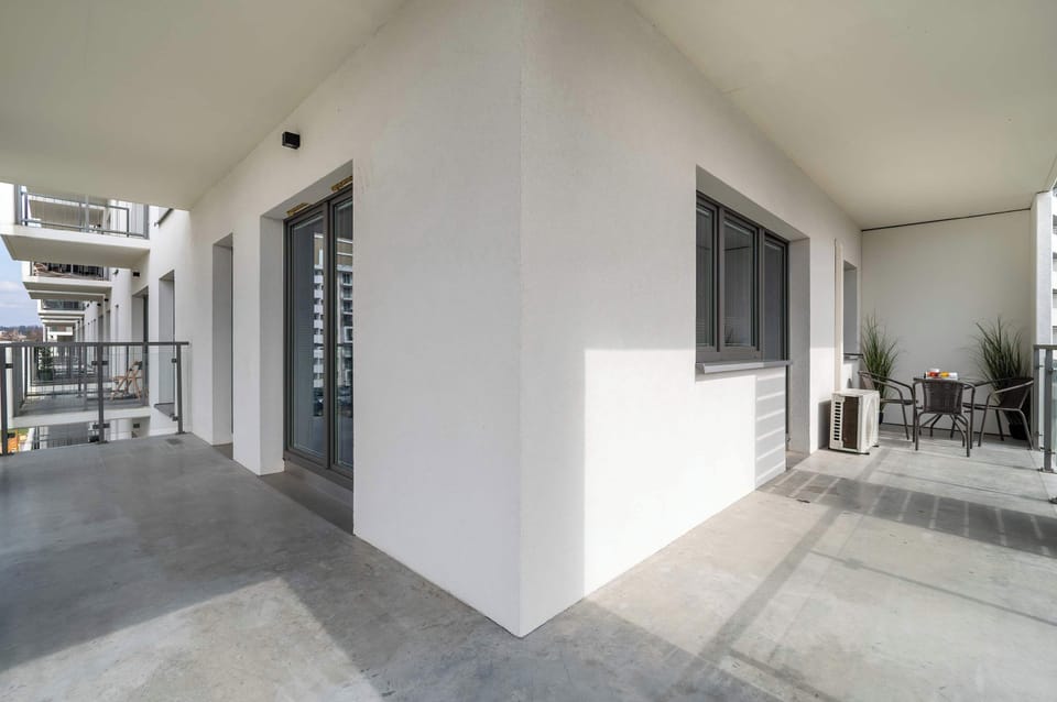 The spacious balcony impresses with its minimalist elegance, where the raw concrete finish works harmoniously with the light-coloured walls to create the perfect place to relax outdoors.