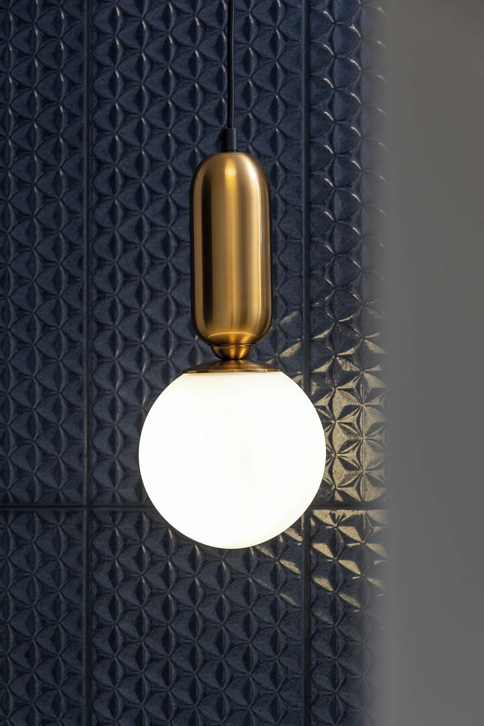A close-up of a modern wall lamp with golden details, placed in the bathroom. The design is elegant and functional.