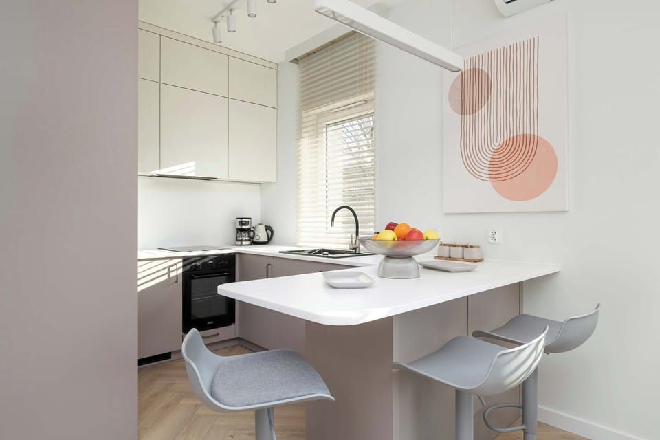 Functional and bright kitchenette with an oven, dishwasher, and electric kettle, complemented by an inviting dining area.