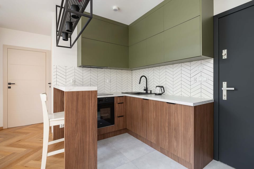 A modern kitchenette with wooden cabinets and built-in appliances. Functional and stylish, ideal for everyday cooking.