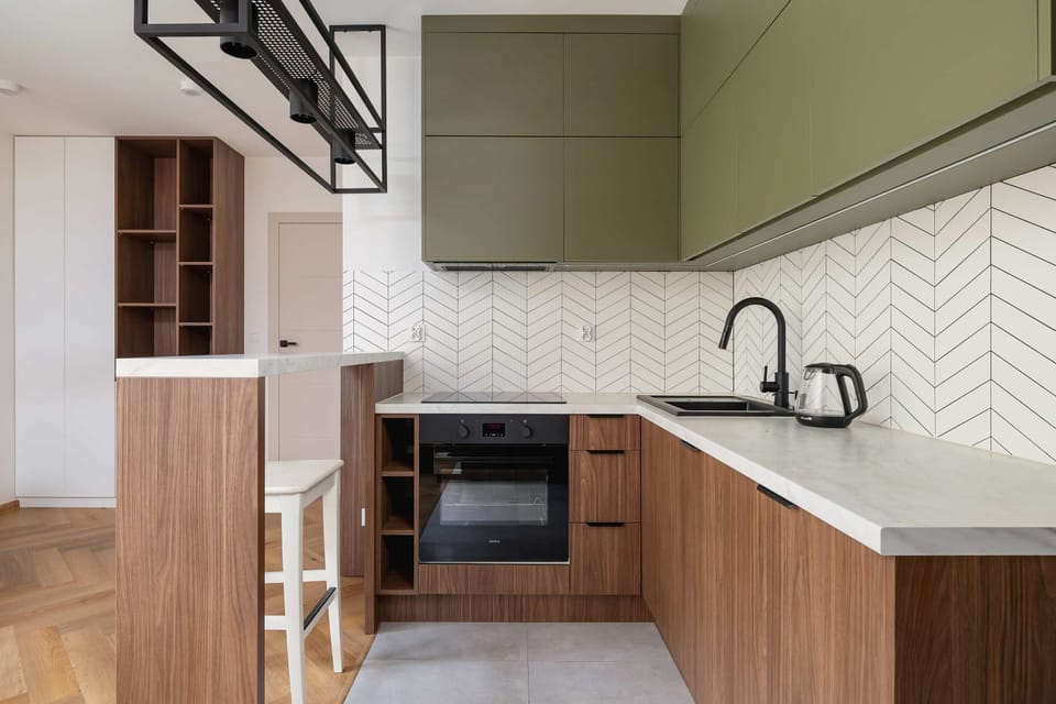 A small yet efficient kitchen corner with modern cabinetry and a sleek design. White tiles and wood finishes provide a clean, minimalist look.