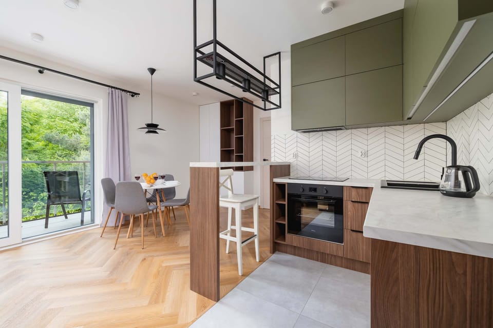 A stylish kitchen with green cabinets, wooden finishes, and built-in appliances. A comfortable place to prepare meals with a contemporary touch.