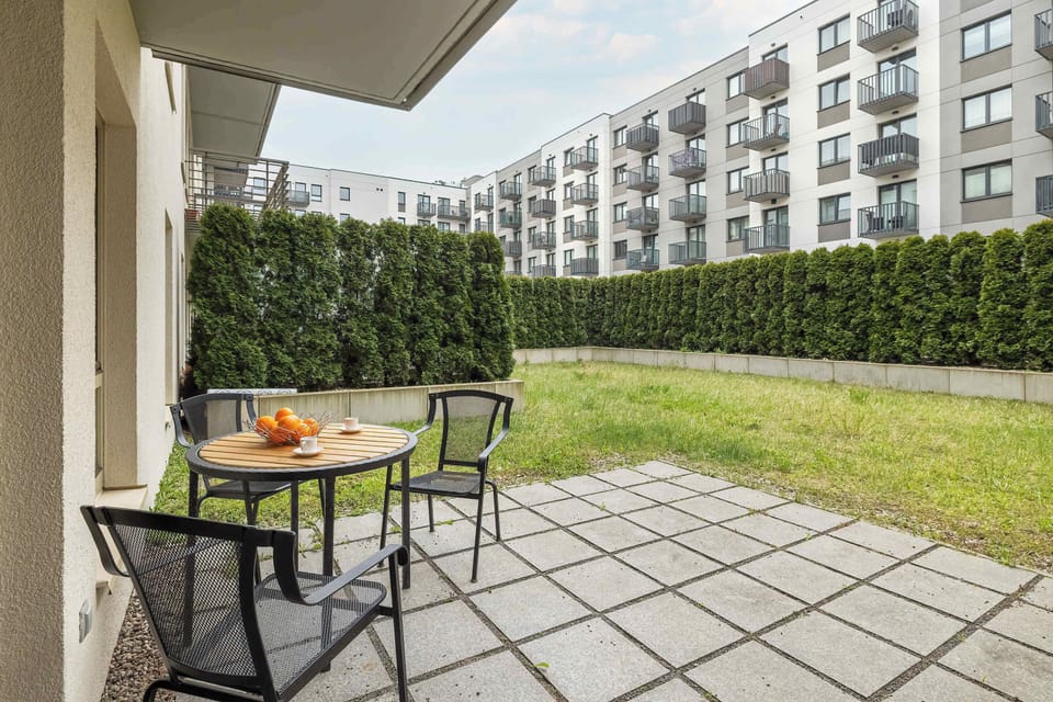 A terrace with a table and two chairs overlooking a grassy courtyard, perfect for outdoor relaxation.