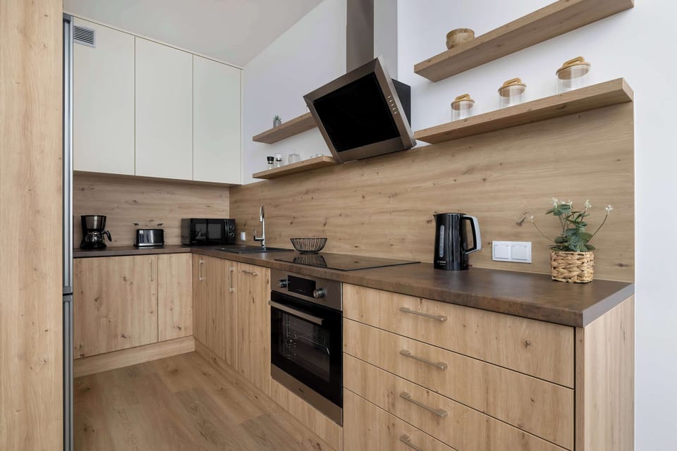 A modern kitchenette with elegant wooden cabinets and stylish black accents exudes functionality and sophisticated design.
