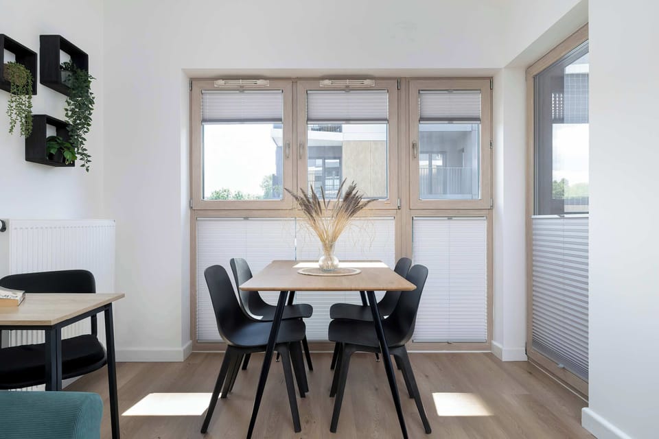 A dining room with a large table, Scandinavian-style chairs, and a window letting in plenty of natural light creates a bright and welcoming space.