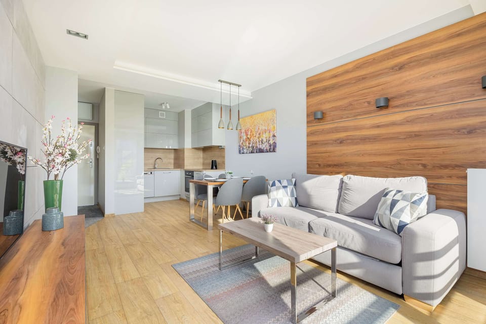 Another view of the living room, showing a cozy seating area with a grey sofa, a wooden coffee table, and a TV stand. This angle emphasizes the stylish and comfortable layout of the space.