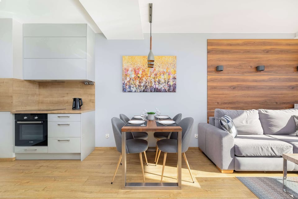 Another angle of the combined living and dining space. The dining area is the focus here, with modern chairs and lighting complementing the wooden flooring and neutral-colored walls.