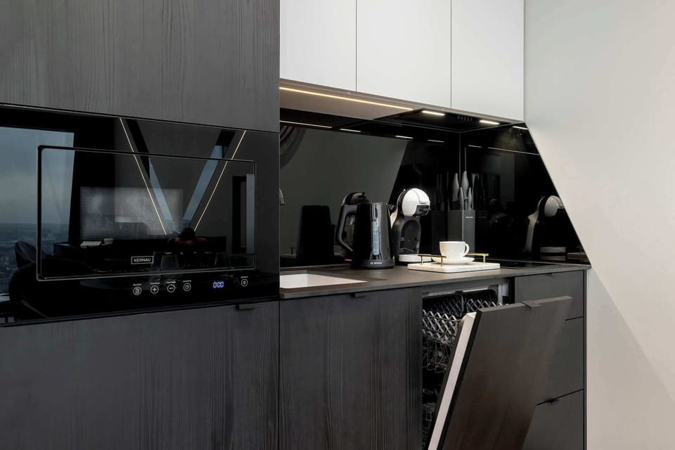 A cozy, modern kitchen area with dark finishes and practical functionality, perfect for small spaces.