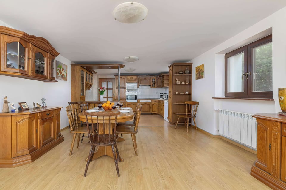 Large, sunlit dining area with solid wood tables, chairs, and cabinetry – ideal for group stays, family gatherings, or alpine-style retreats.